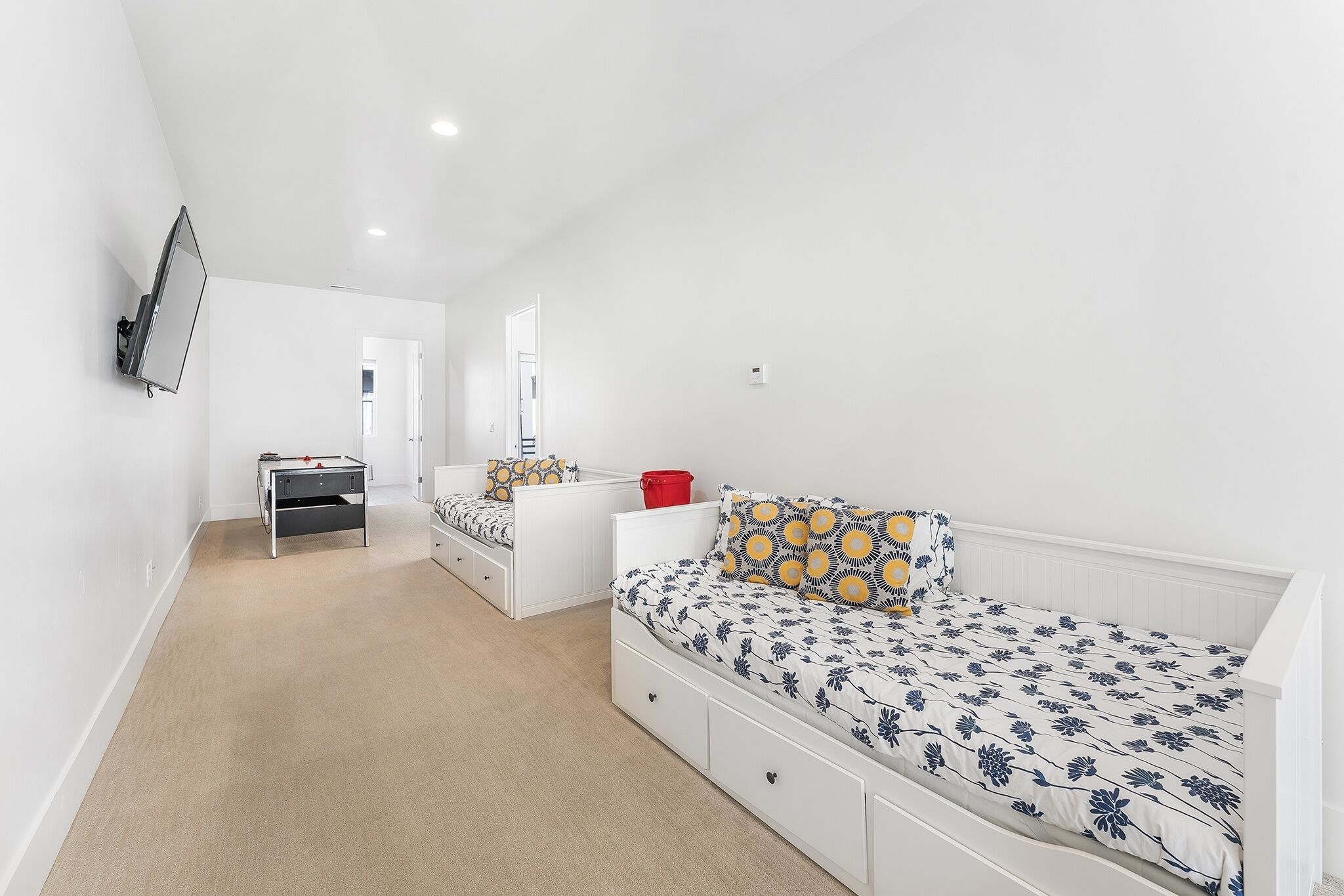 A bedroom with a bed, a desk, and a television mounted on the wall.