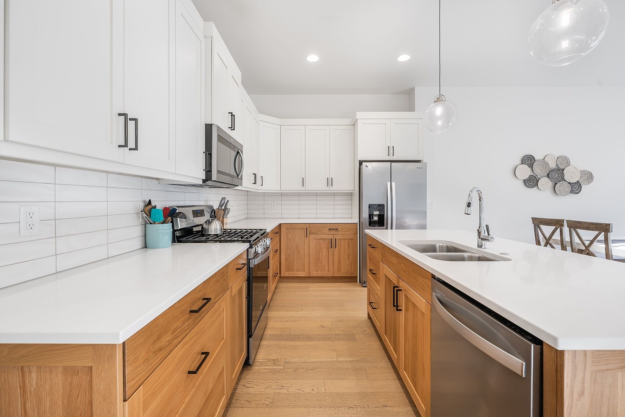 A modern kitchen with white cabinets, a stainless steel refrigerator, and a wooden countertop.