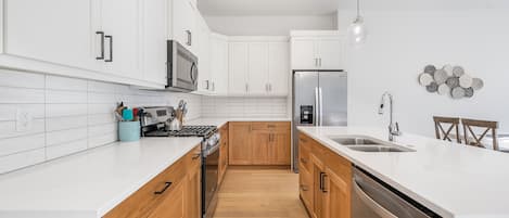 Una cocina moderna con armarios blancos, un refrigerador de acero inoxidable y una encimera de madera.