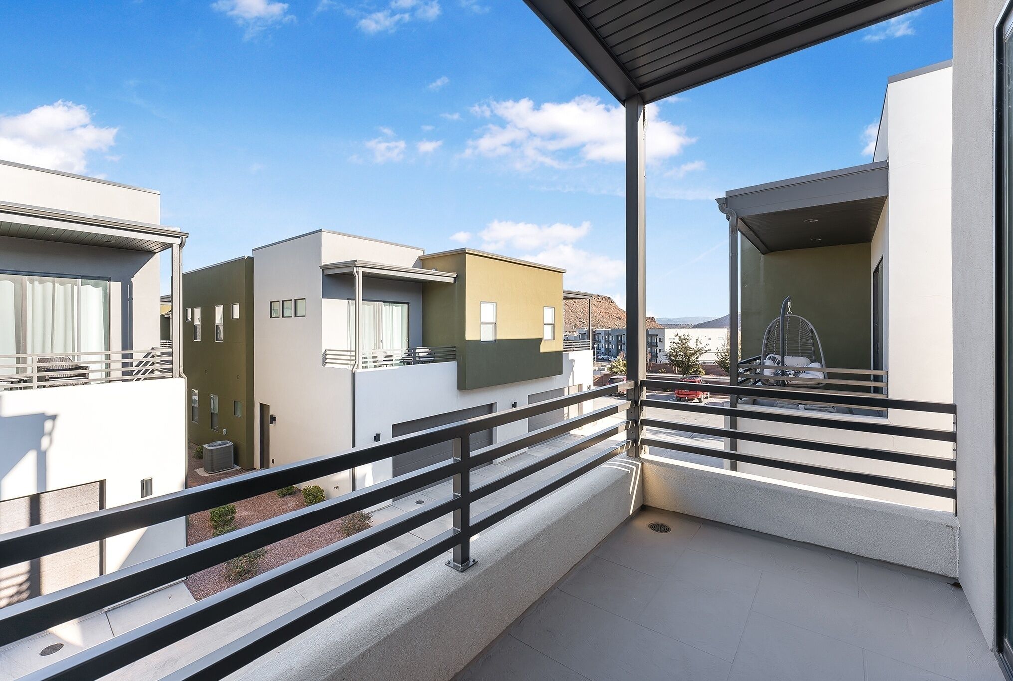 A modern apartment complex with balconies, a covered outdoor area, and a view of the surrounding buildings.