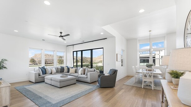 A spacious living room with a sectional sofa, a dining area with a table and chairs, and large windows offering a view of the outdoors. - Villa #22 At Bloomington Country Club - Fairway To Heaven 3 Bedroom Condo (St. George)