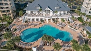 A large resort with a central swimming pool, multiple balconies, and a view of the surrounding area.