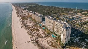 A coastal hotel with multiple high-rise buildings, a beach, and a pool area.