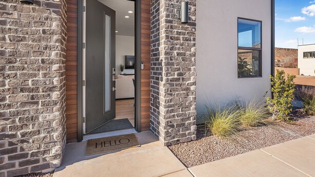 Una casa moderna con fachada de piedra, puerta de madera y una ventana pequeña.