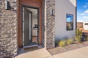Una casa moderna con fachada de piedra, puerta de madera y una ventana pequeña.