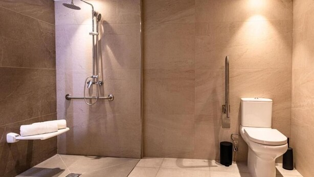 A modern bathroom with a shower, toilet, and a towel rack. - CA Sand Dune Hotel (Birzebbuga)