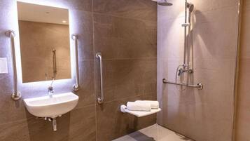 Un baño moderno con lavamanos, espejo y ducha.