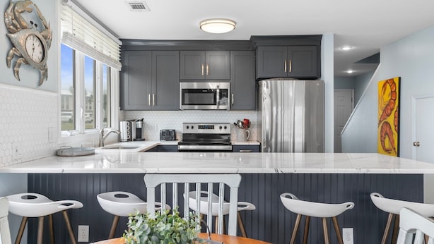 A modern kitchen with grey cabinets, stainless steel appliances, and a white marble countertop. - Family Tides 107 3 Bedroom Condo (Miramar Beach)