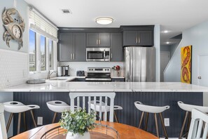 A modern kitchen with grey cabinets, stainless steel appliances, and a white marble countertop. - Family Tides 107 3 Bedroom Condo (Miramar Beach)