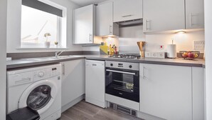 Cocina compacta con lavadora, horno y ventana con plantas.