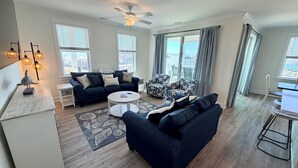 A modern living room with a dark blue sofa, a round coffee table, and a ceiling fan.