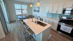 A modern kitchen with a central island, stainless steel appliances, and a view of the city through the window.
