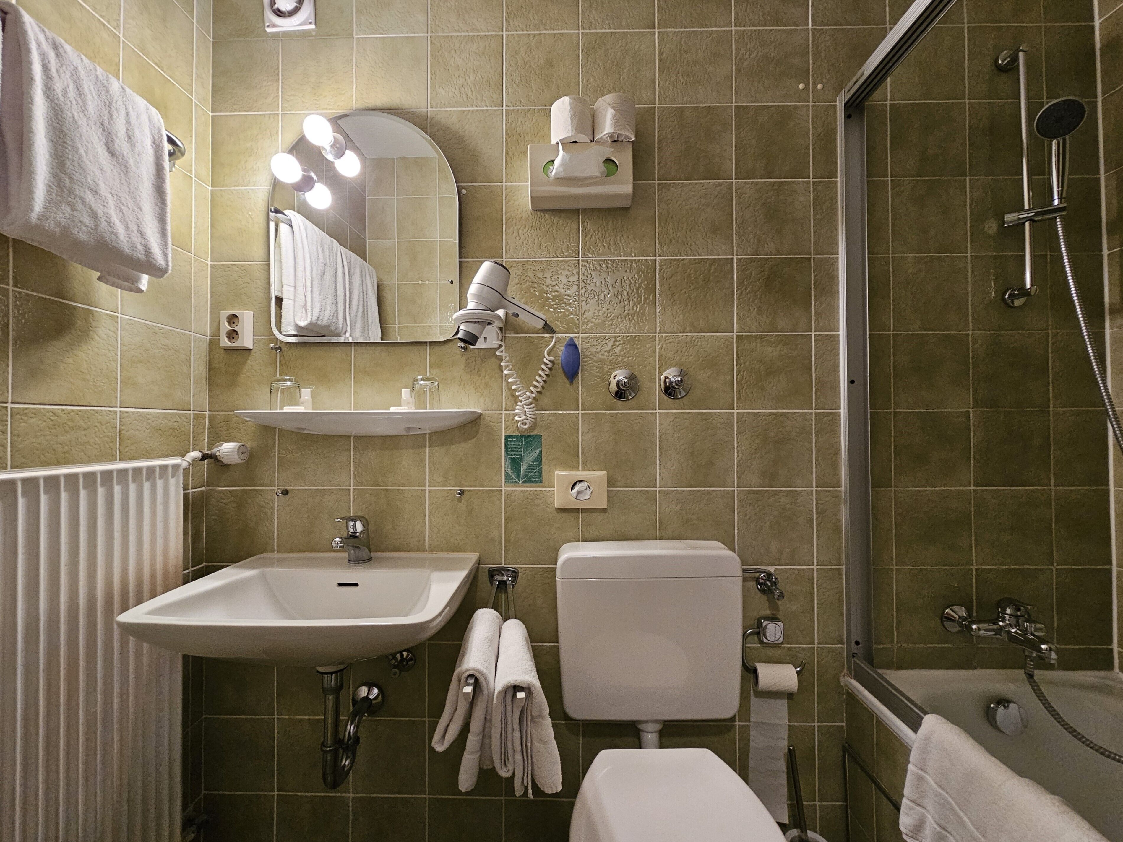 A bathroom with a sink, mirror, towel rack, toilet, and shower.