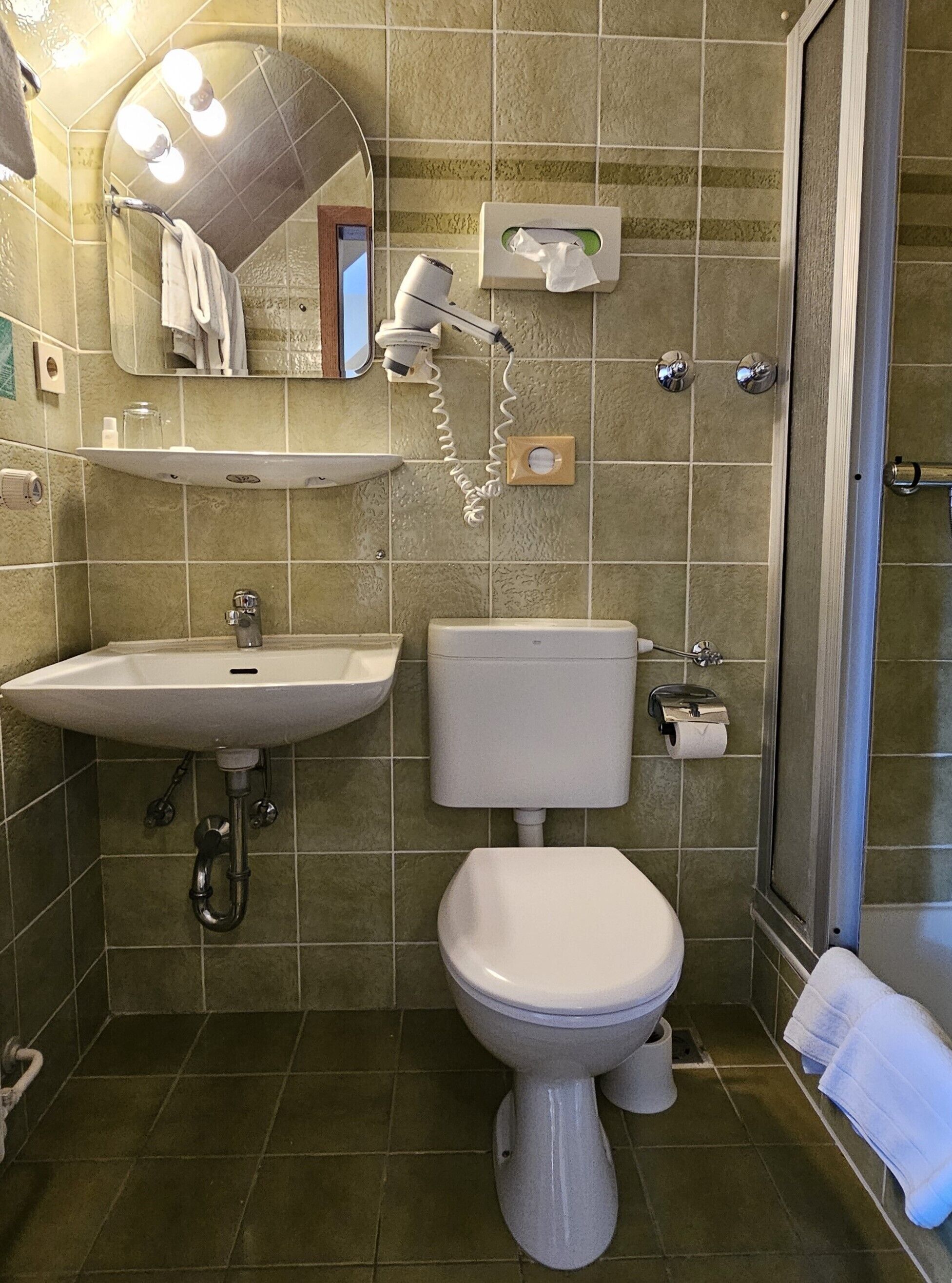 Un bagno con lavandino, WC e doccia.