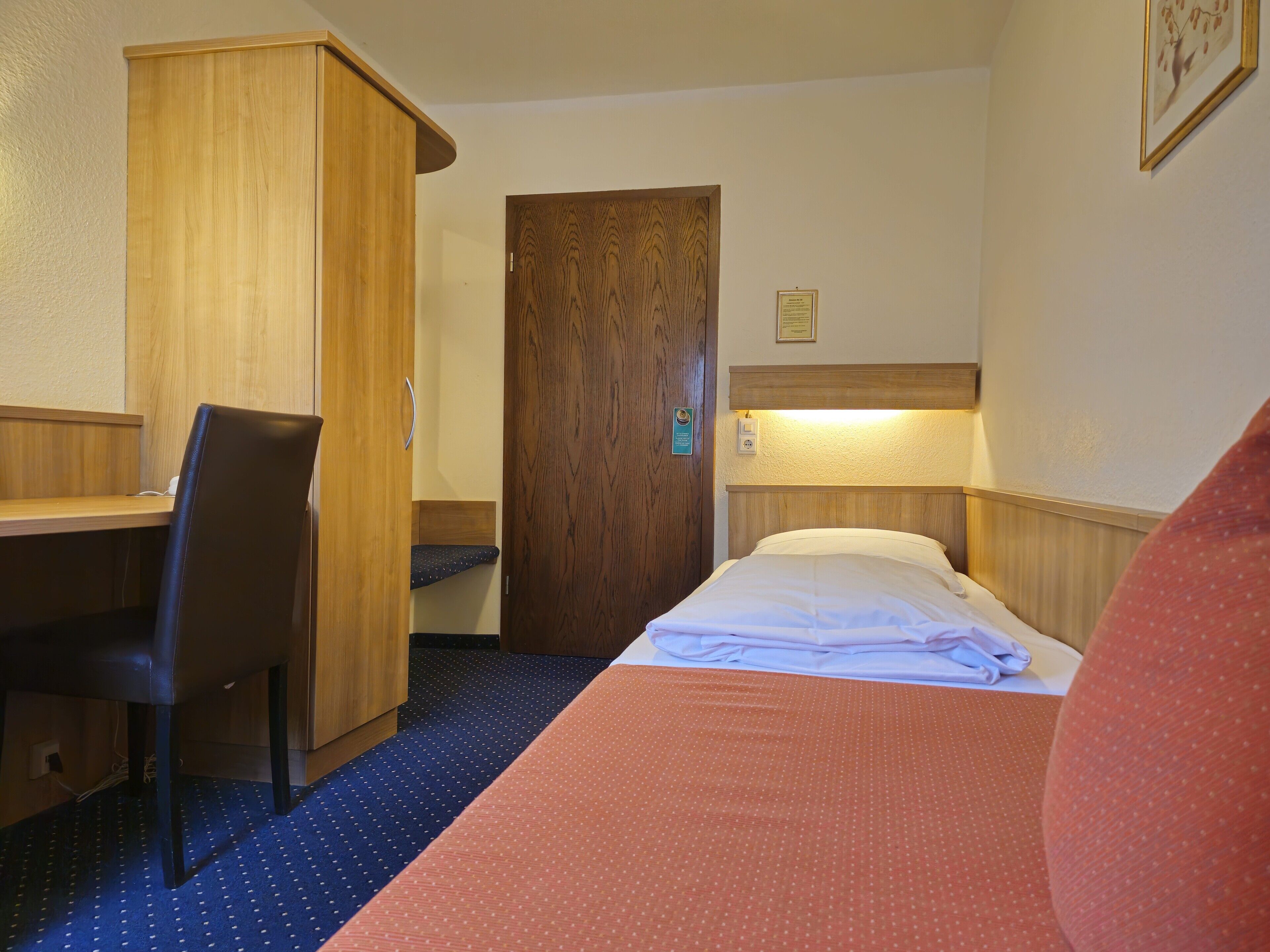 Una habitación de hotel con cama, escritorio, silla y armario de madera.