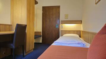 Una habitación de hotel con cama, escritorio, silla y armario de madera.
