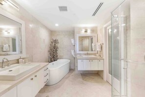 Een moderne badkamer met een vrijstaand bad, een douche met glazen wanden en een wastafel met spiegel.