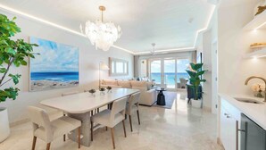 Un salon moderne avec un coin repas, de grandes fenêtres et une vue sur l’océan.