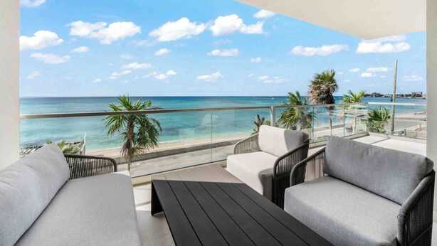 Ein Balkon mit Meerblick, einer Couch und einem Tisch.