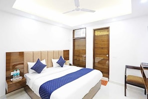 A hotel room with a bed, nightstand, desk, chair, and wardrobe. - Hotel Vijaydeep Place Near Delhi Airport (New Delhi)