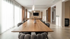 A spacious, modern dining area with a long wooden table, comfortable seating, and a central decorative vase. - Villa Freedom (Vodice)