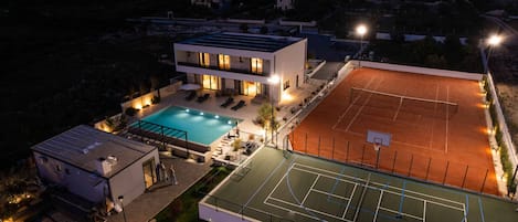 A modern building with a swimming pool and a tennis court.