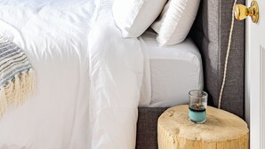 A bedroom with a bed, a bedside table with a glass, and a wall-mounted light fixture.