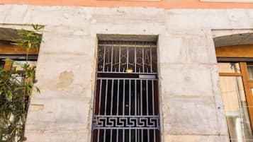 Une façade d’immeuble avec une fenêtre ornée de barreaux en métal décoratifs et portant le numéro « 32 ».
