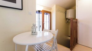 A small, round white table with a white chair, a white lantern, and a wooden door with a white panel. - Charming studio under the roof in Grenoble city center (Grenoble)