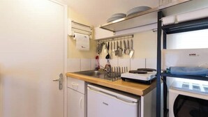 A compact kitchen with a dishwasher, a sink, and a countertop with various utensils. - Charming studio under the roof in Grenoble city center (Grenoble)