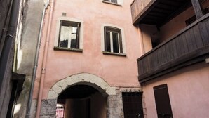 A pink building with a balcony and an arched entrance. - Charming studio under the roof in Grenoble city center (Grenoble)