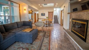 A spacious living room with a sectional sofa, a dining table with chairs, a fireplace, and a ceiling fan.