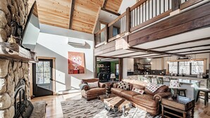 A spacious living room with a stone fireplace, leather sofas, and a large wooden ceiling. - River access/Golf 2 miles/hiking/skiing/hot tub/sauna (Newry)