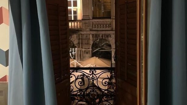 Un pasillo estrecho con una reja de hierro que da a un balcón.