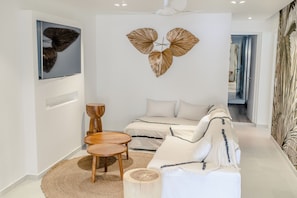A modern living room with a sofa, two wooden side tables, a round rug, and a wall-mounted decorative piece.