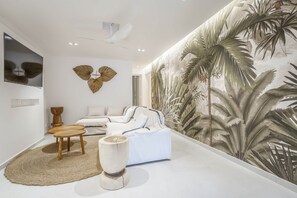 A modern interior with a large wall mural, a sofa, a coffee table, and a decorative wooden sculpture.