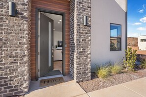 A modern house with a stone facade, a wooden door, and a small window.