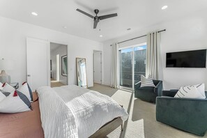 Une chambre moderne équipée d’un lit, d’un ventilateur de plafond, d’une télévision et d’un balcon avec vue.