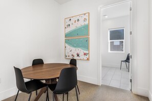 Une salle de conférence avec une table en bois et des chaises noires, un grand tableau abstrait accroché au mur et une porte donnant sur une autre pièce.