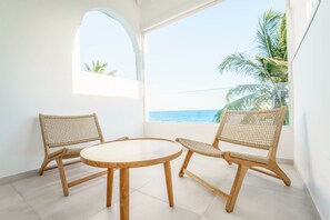 A balcony with two wicker chairs and a round wooden table, overlooking a clear blue sea and palm trees. - Luxury with full sea and beach view (Saint-Francois)