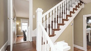 Un escalier avec des balustrades blanches et des marches en bois menant à l’étage supérieur.