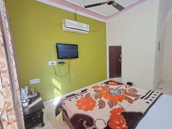 Un dormitorio con cama, aire acondicionado, televisor y puerta.