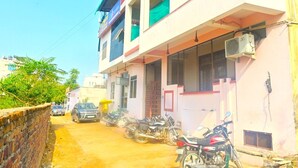 Un immeuble à plusieurs étages, avec une entrée au rez-de-chaussée, un balcon au deuxième étage et une moto garée devant.