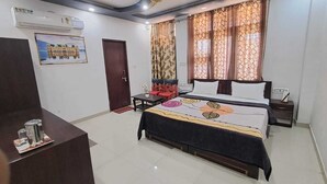 Une chambre d’hôtel équipée d’un lit, d’un bureau, d’une chaise, d’un ventilateur de plafond et d’une fenêtre avec des rideaux.