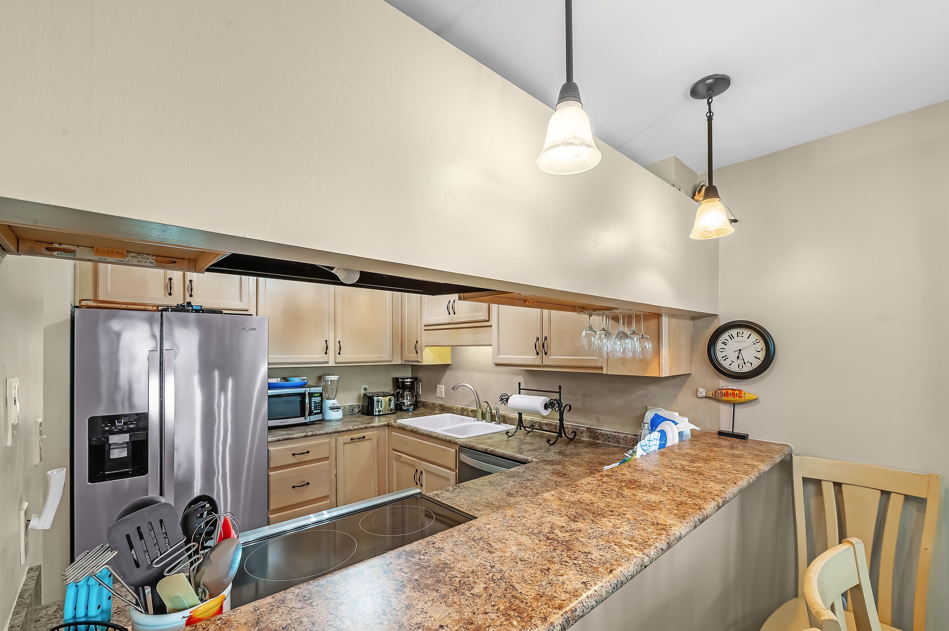 A modern kitchen with stainless steel appliances, granite countertops, and pendant lighting.
