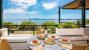 Una mesa preparada para una comida con vistas al mar y a las montañas.