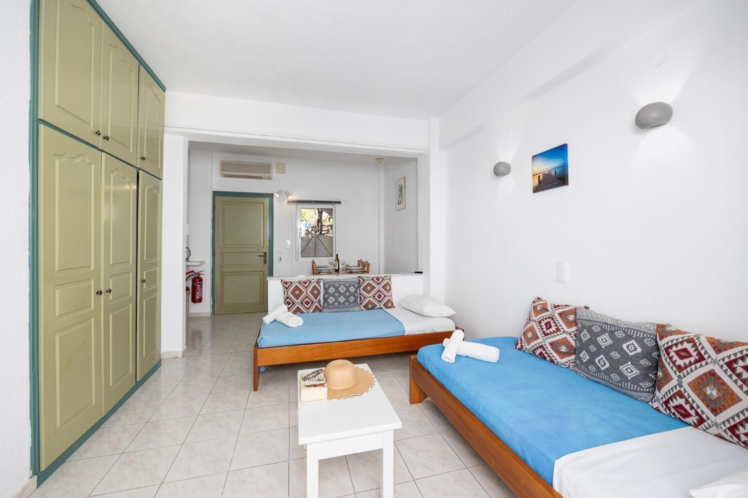 Ein kleines Hotelzimmer mit zwei Einzelbetten, einem Tisch und einem Kleiderschrank.