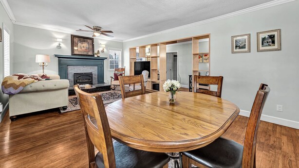 A dining area with a wooden table and chairs, a fireplace, and a ceiling fan. - University Place, family stay, practically on campus (Siloam Springs)