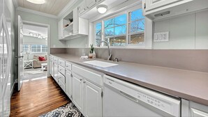 A modern kitchen with white cabinets, a stainless steel sink, and a window with a view of the outside. - University Place, family stay, practically on campus (Siloam Springs)