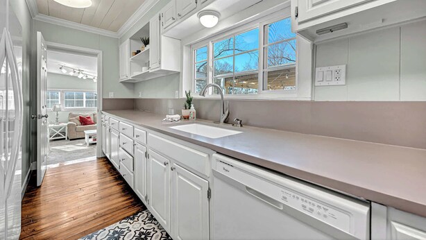 A modern kitchen with white cabinets, a stainless steel sink, and a window with a view of the outside. - University Place, family stay, practically on campus (Siloam Springs)